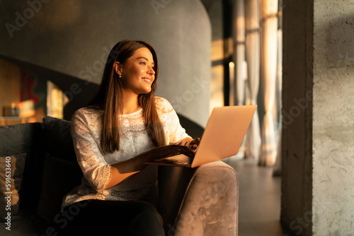 Portrait of a young smiling woman working on the laptop