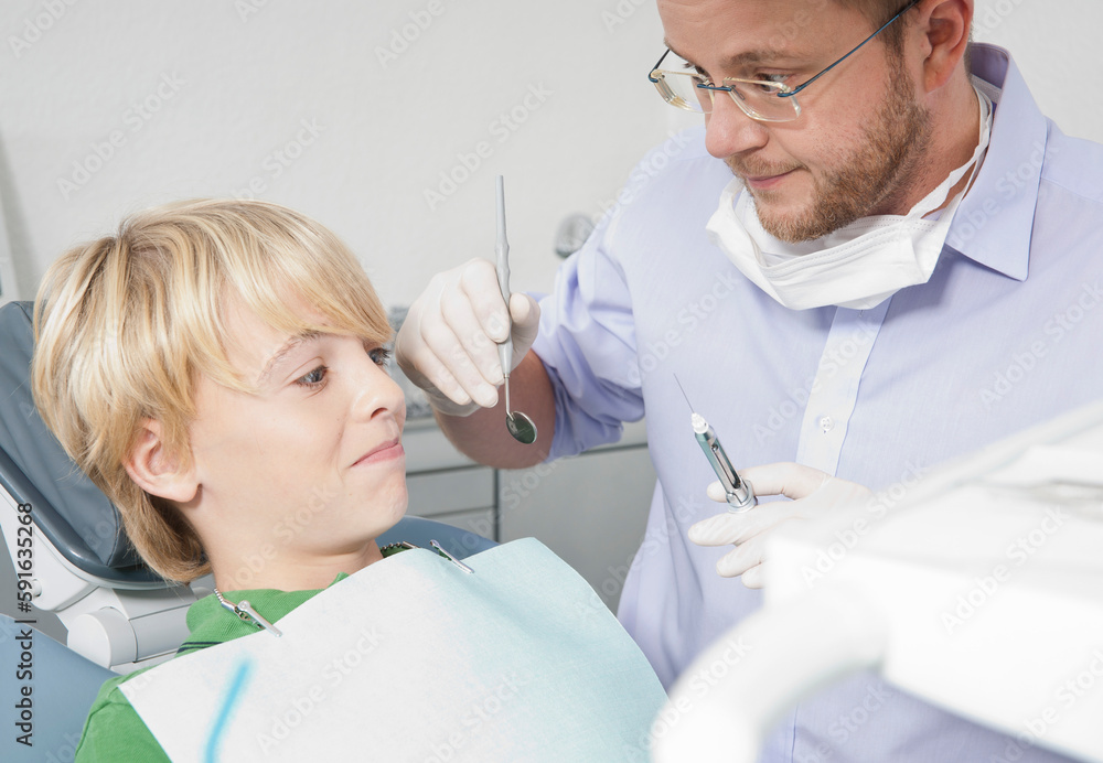 Boy looking Anxiously at Dentist holding a Needle during Appointment, Germany Boy looking Anxiously at Dentist holding a Needle during Appointment, Germany
