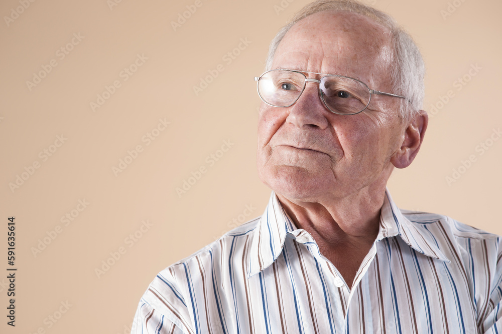 Portrait of Senior Man wearing Aviator Eyeglasses and Looking up into the Distance with Confident Expression in Studio on Beige Background Portrait of Senior Man wearing Aviator Eyeglasses and Looking up into the Distance with Confident Expression in Studio on Beige Background