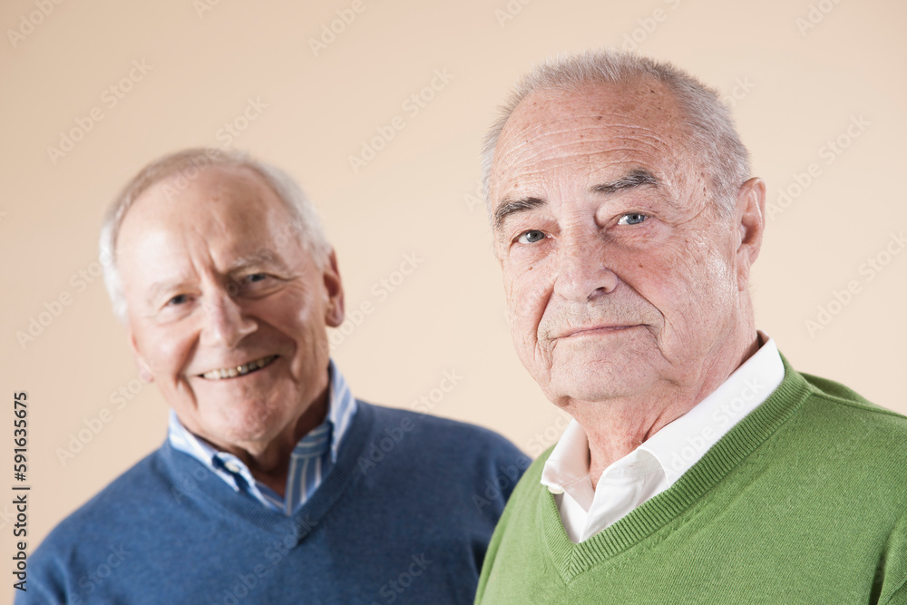 Portrait of Two Senior Men Looking at Camera, Studio Shot on Beige Background Portrait of Two Senior Men Looking at Camera, Studio Shot on Beige Background