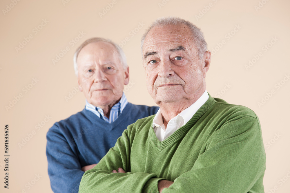 Portrait of Two Senior Men Looking at Camera, Studio Shot on Beige Background Portrait of Two Senior Men Looking at Camera, Studio Shot on Beige Background