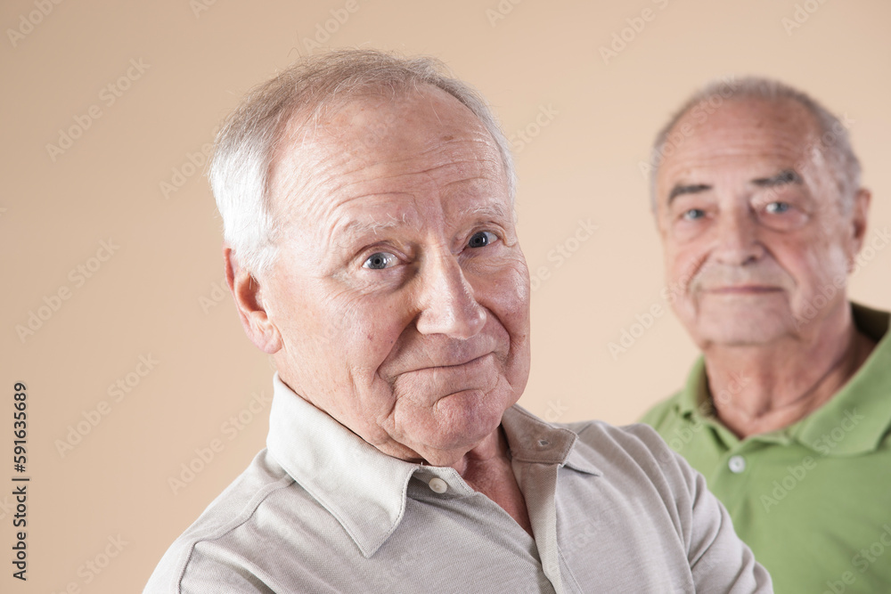 Portrait of Two Senior Men Looking at Camera, Studio Shot on Beige Background Portrait of Two Senior Men Looking at Camera, Studio Shot on Beige Background