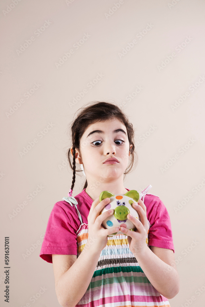 Portrait of Girl Looking Cross Eyed at Piggy Bank in Studio Portrait of Girl Looking Cross Eyed at Piggy Bank in Studio