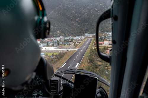 Famous Lukla airport with its inclined airstrip seen from the perspective of helicopter pilot during landing