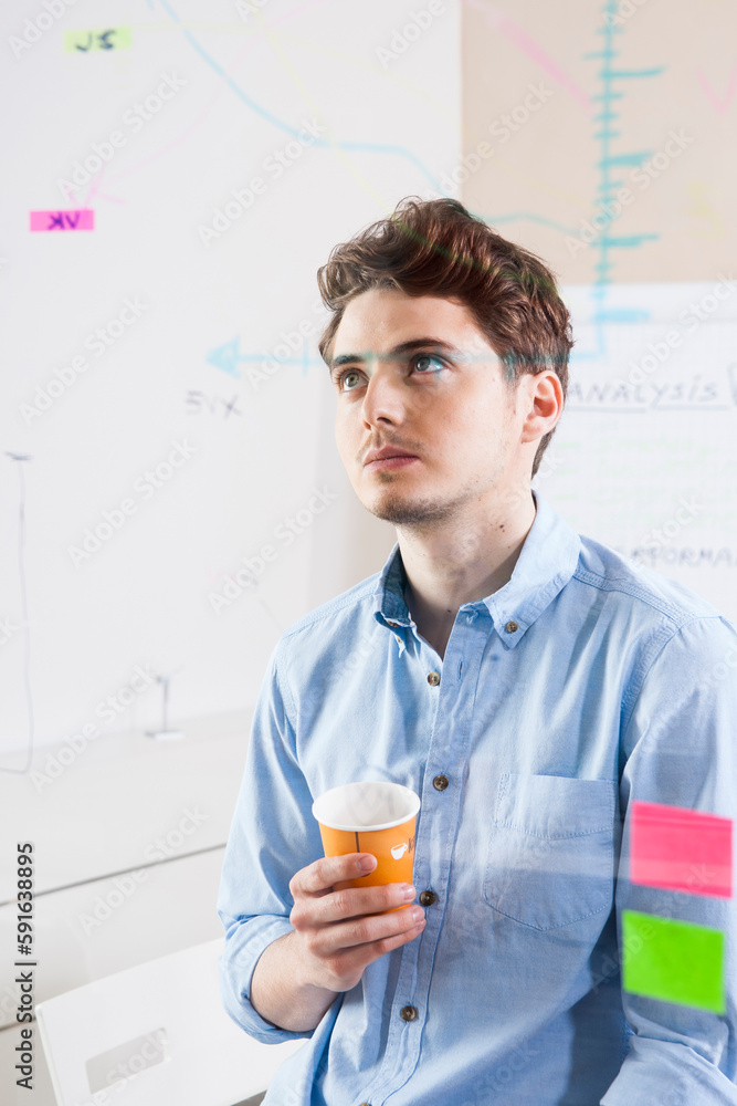 Young Man Working in an Office, Looking Through Glass Board, Germany Young Man Working in an Office, Looking Through Glass Board, Germany