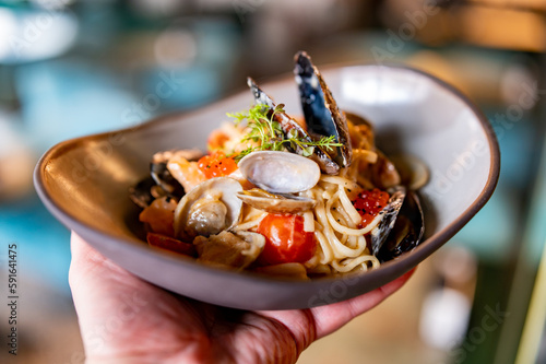 Quadro su tela man hand hold Italian spaghetti pasta marinara with Clams, Prawns, Mussels, toma