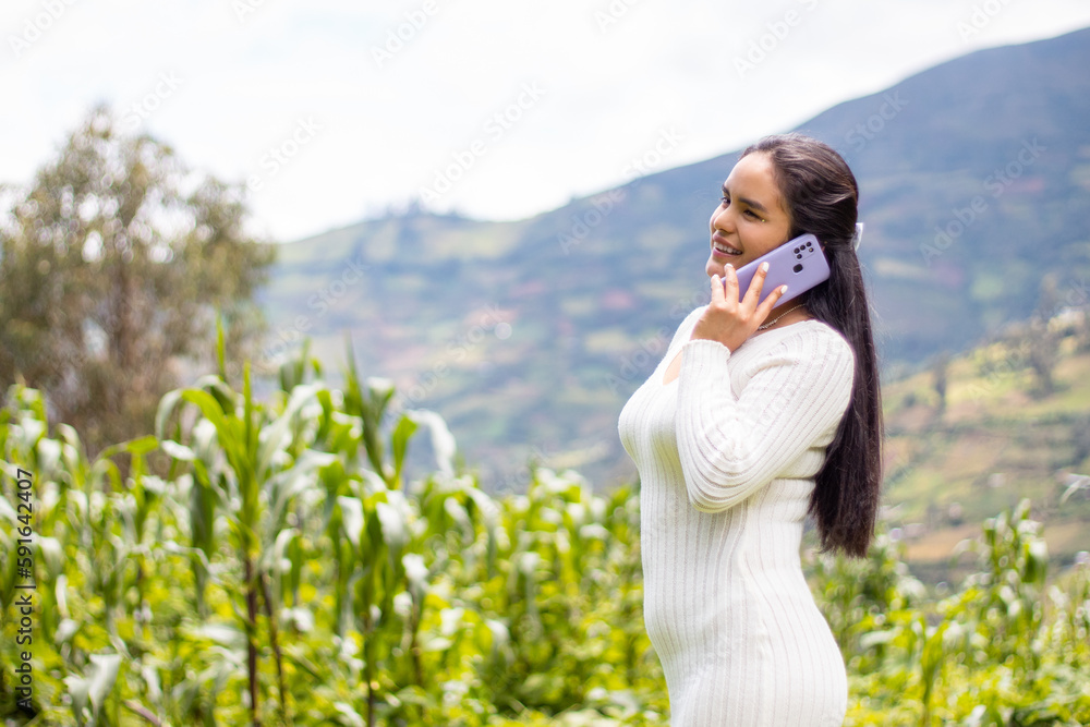 Alegre chica hispana en un top blanco hablando por teléfono sobre un fondo verde Alegre chica hispana en un top blanco hablando por teléfono sobre un fondo verde