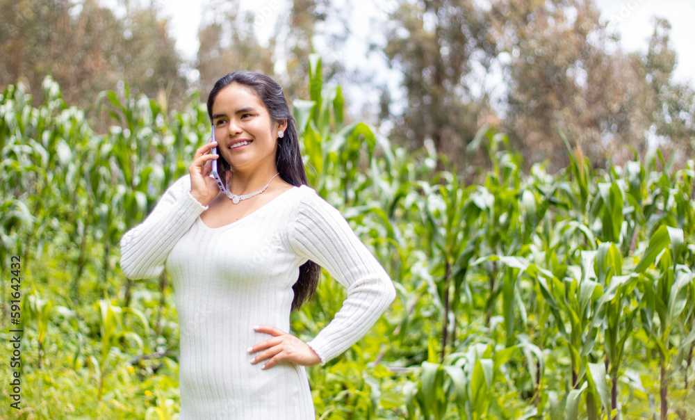 Alegre chica hispana en un top blanco hablando por teléfono sobre un fondo verde Alegre chica hispana en un top blanco hablando por teléfono sobre un fondo verde
