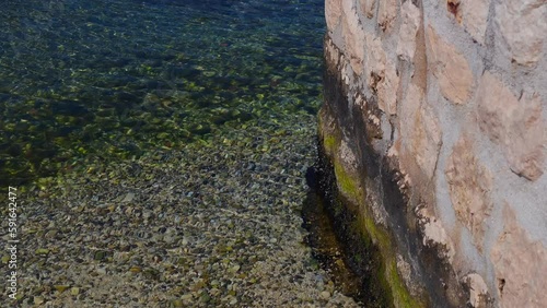 Calm Crystal Water Sea with Moss-Covered Wall