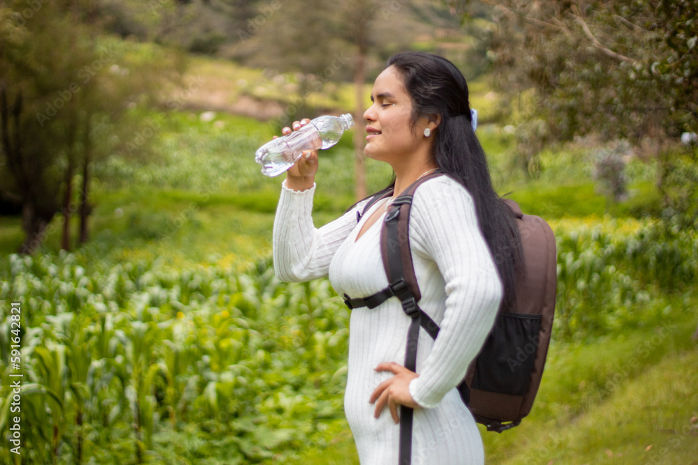 Caminante con una mochila  bebiendo agua contra un cielo azul nublado,cielo azul,paisaje,explorar,cocepto turismo,