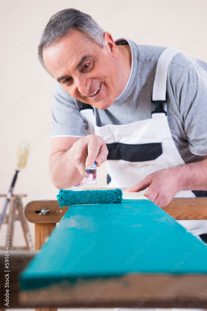 Senior Man Painting Board with Blue Paint, Studio Shot Senior Man Painting Board with Blue Paint, Studio Shot