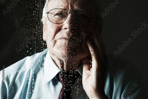Elderly Man Looking out Window on Rainy Day