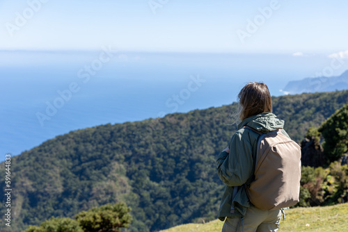 Tablou pe pânză Woman with a backpack taking in the majestic view of a coastal landscape