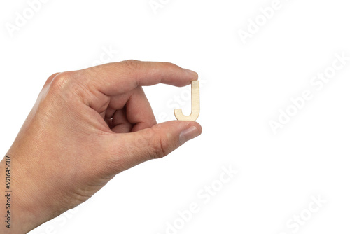 Close up of a person's hand holding a small wooden letter J isolated on a white background