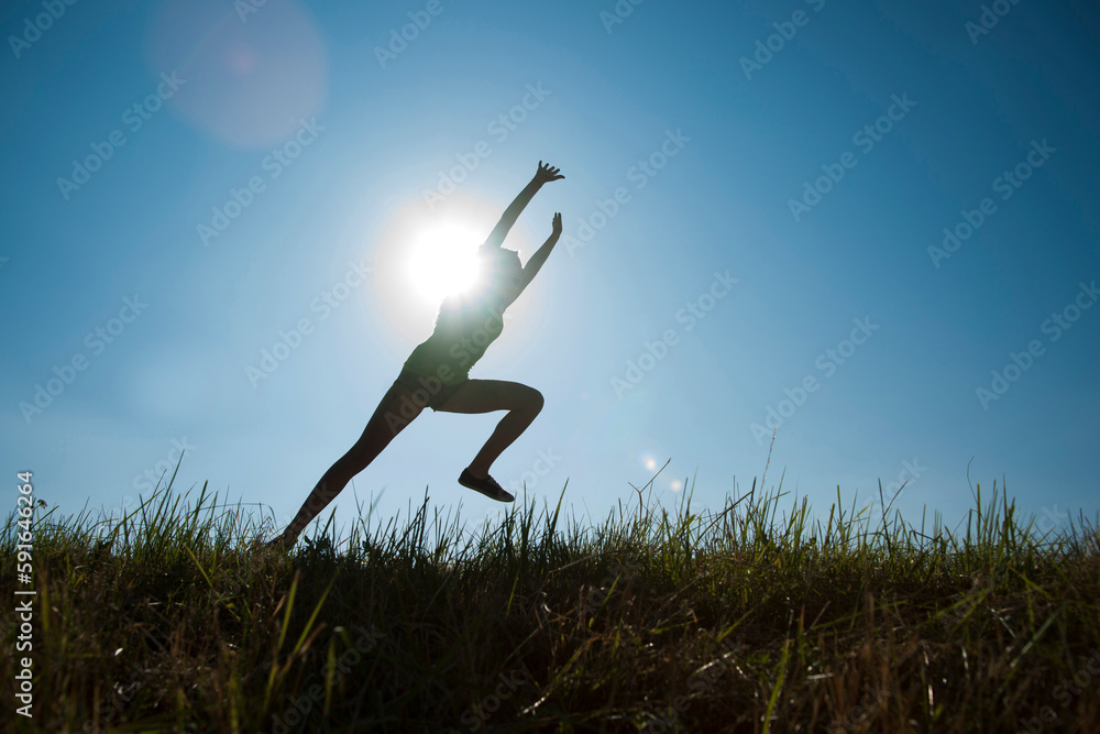 Silhouette of teenaged girl running in field, Germany