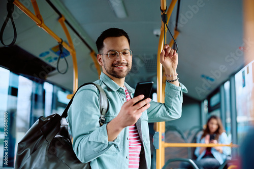 Young man using mobile phone while commuting by public transport.