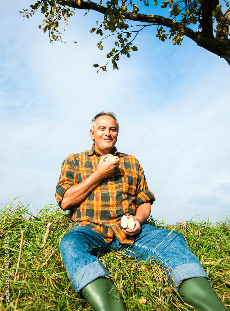 Portrait of farmer sitting in field eating apple, Germany Portrait of farmer sitting in field eating apple, Germany
