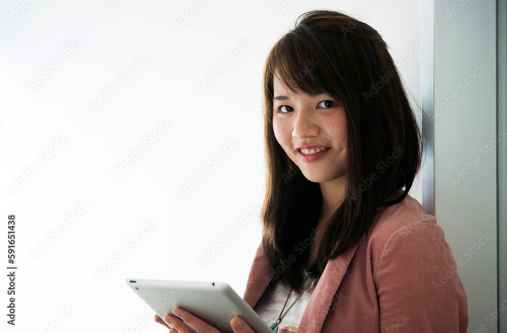 Close-up portrait of young woman holding tablet computer, looking at camera and smiling, Germany Close-up portrait of young woman holding tablet computer, looking at camera and smiling, Germany