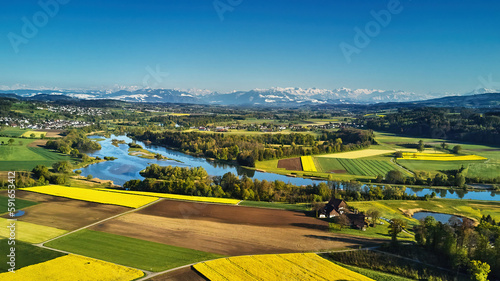 Blick über den Flachsee (Reuss) umgeben von einem bunten Mosaik aus Wald, Wiesen, Rapsfeldern und Ackerflächen, die sich bis zu den Bergen hinziehen. Wolkenloser, stahlblauer Himmel.. photo