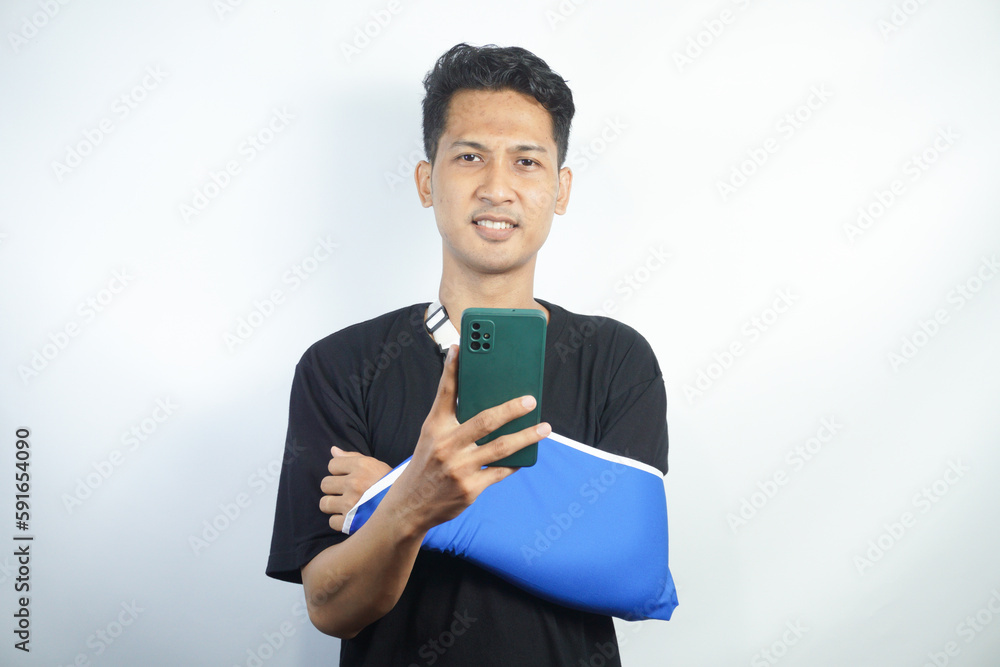 Young man in casual clothes with broken hand using cellphone to talk to doctor via video conference Young man in casual clothes with broken hand using cellphone to talk to doctor via video conference