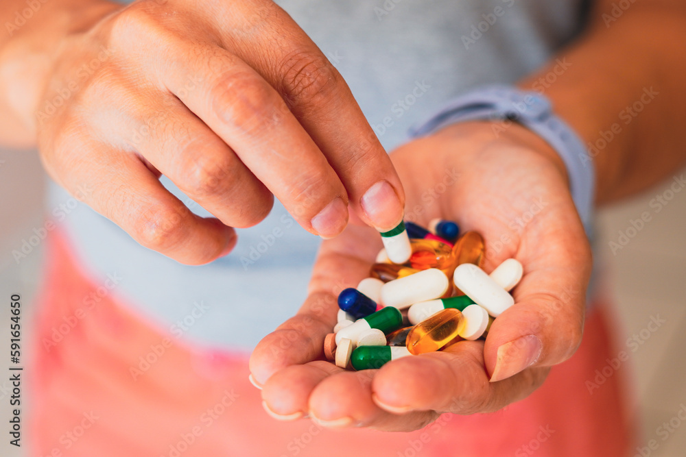 A person holds several medicine pills in his hand
