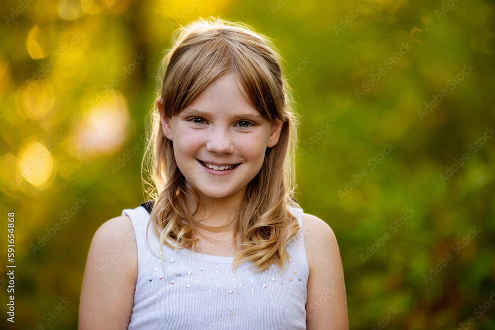 Close-up outdoor portrait of a sweet young girl with blond hair with autumn colours in the background; Edmonton, Alberta, Canada Close-up outdoor portrait of a sweet young girl with blond hair with autumn colours in the background; Edmonton, Alberta, Canada