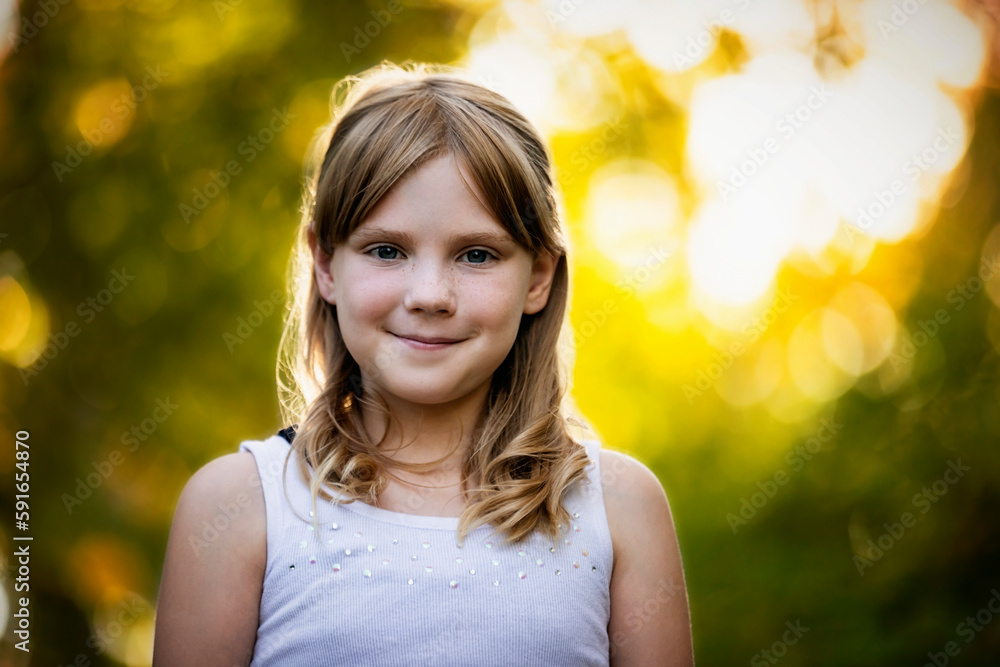 Close-up outdoor portrait of a sweet young girl with blond hair with autumn colours in the background; Edmonton, Alberta, Canada Close-up outdoor portrait of a sweet young girl with blond hair with autumn colours in the background; Edmonton, Alberta, Canada