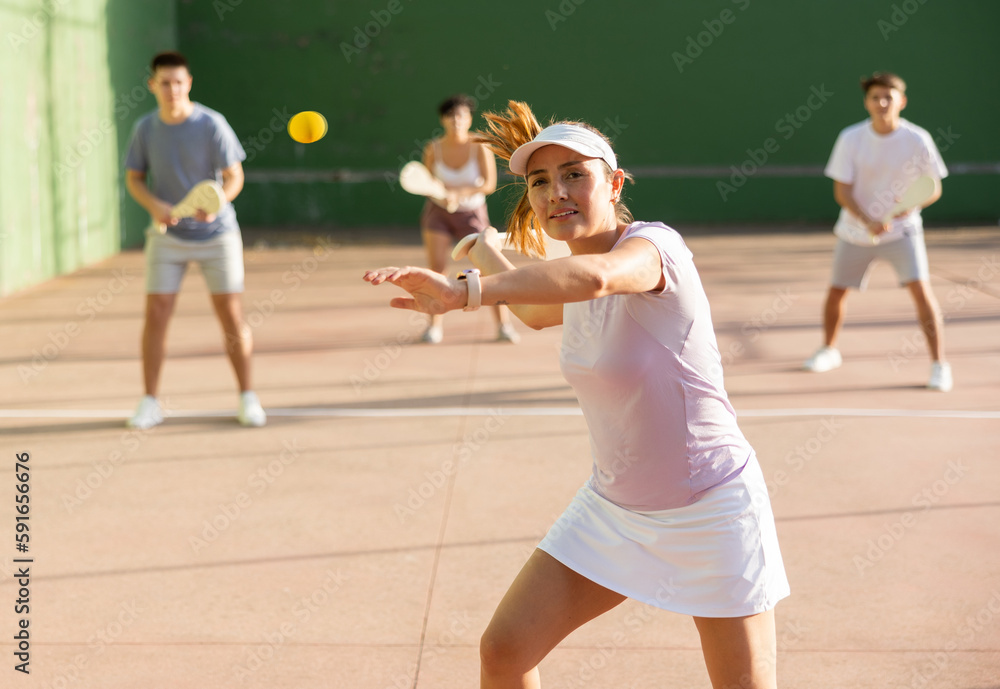 Active womans with enthusiasm playing paleta fronton group on the outdoor court