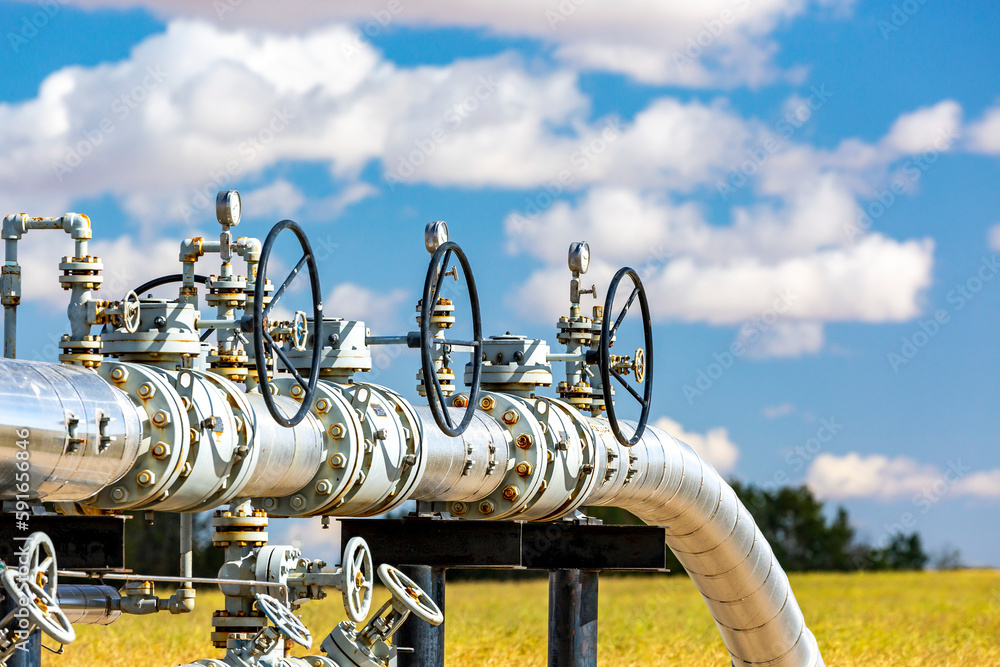 Oil pipeline with values, blue sky and clouds, West of Airdrie; Alberta