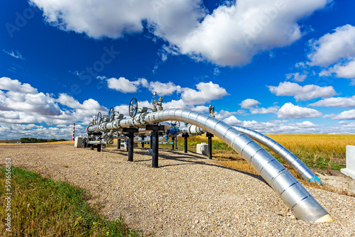 Oil pipeline with values, blue sky and clouds, West of Airdrie; Alberta, Canada photo
