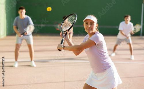 Sportive woman in shorts and t-shirt playing frontenis on outdoors court © JackF