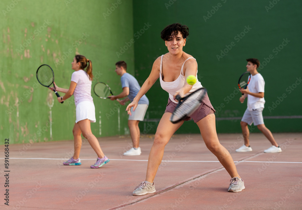 Focused woman playing frontenis with partners at sunny day, healthy lifestyle concept