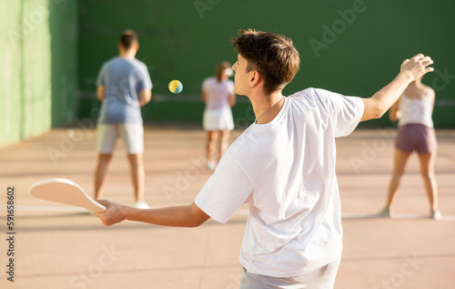 Concentrated young man paleta fronton player hitting ball with a racket photo