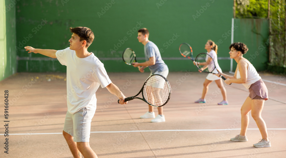 Focused man playing frontenis with partners at sunny day, healthy lifestyle concept