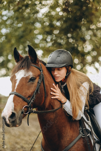 A young woman jockey lies on her horse and hugs her.