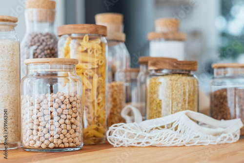 Zero waste concept. Textile eco-bags, glass jars with grocery on a wooden table in the kitchen. Eco-friendly reuse concept. Selective focus.  photo