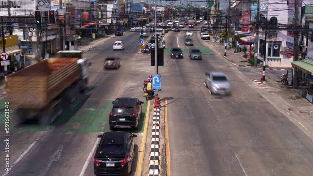 Asphalt road at asian street with busy left side traffic filmed in timelapse at summer day. Cityscape of crossway with driving cars and bikes. Infrastructure of town in Thailand. Transportation theme. Asphalt road at asian street with busy left side traffic filmed in timelapse at summer day. Cityscape of crossway with driving cars and bikes. Infrastructure of town in Thailand. Transportation theme.