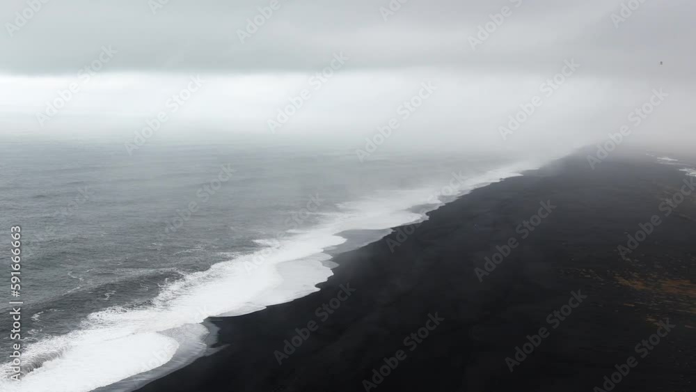 Picturesque dramatic popular panorama to endless ocean black volcanic sand beach from Dyrholaey Cape, Vik, South Iceland in overcast day. Vestmannaeyjar islands Picturesque dramatic popular panorama to endless ocean black volcanic sand beach from Dyrholaey Cape, Vik, South Iceland in overcast day. Vestmannaeyjar islands