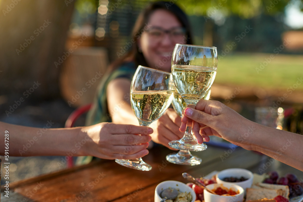 Three female friends make a toast with glasses of sparkling wine at sunset