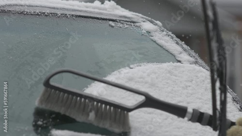Snow is brushed off a car's windshield
