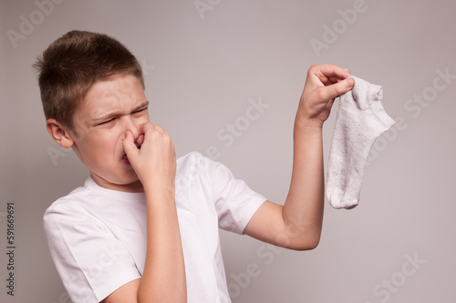the boy closes his nose from the horrible stench of dirty socks