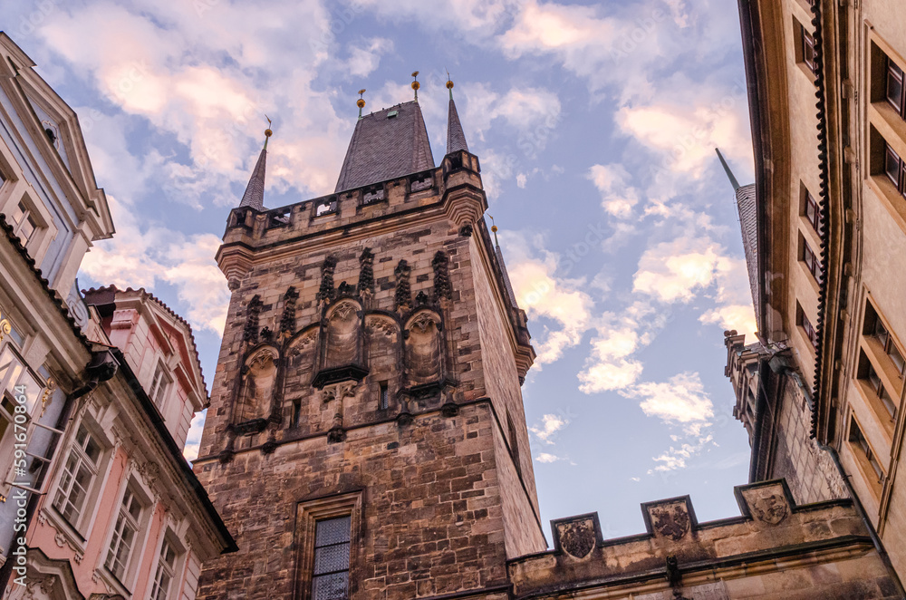 A morning view of the top of a medieval stone tower with statues on an ancient bridge in Prague, Czech Republic. 