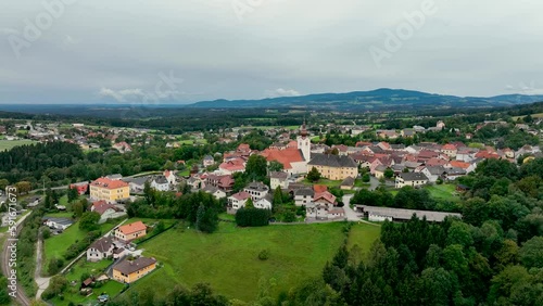 ALPS, AUSTRIA - OCTOBER, 2022: Aerial view of austrian mountain village Lendorf and beautiful valley. Green meadows and autumn forest with yellow leaves around. photo