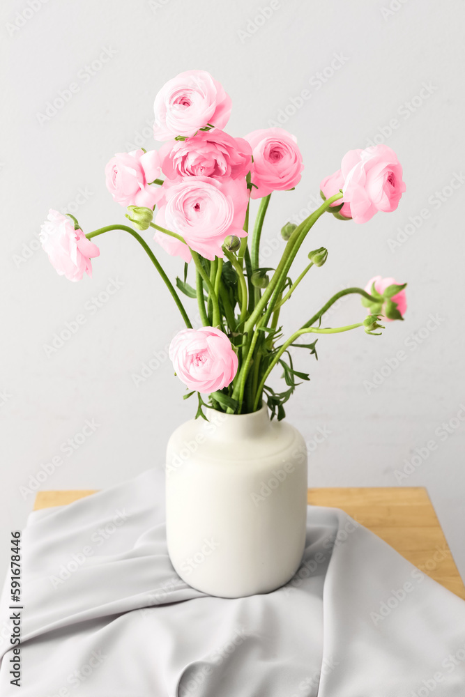 Vase with pink ranunculus flowers on table in room Vase with pink ranunculus flowers on table in room