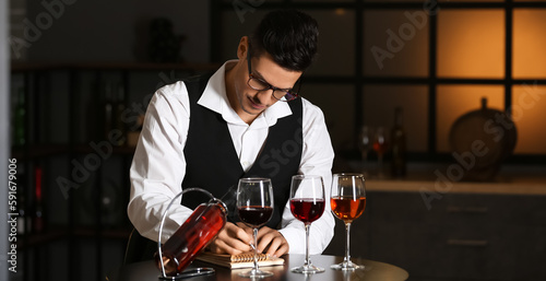 Young male sommelier tastin...