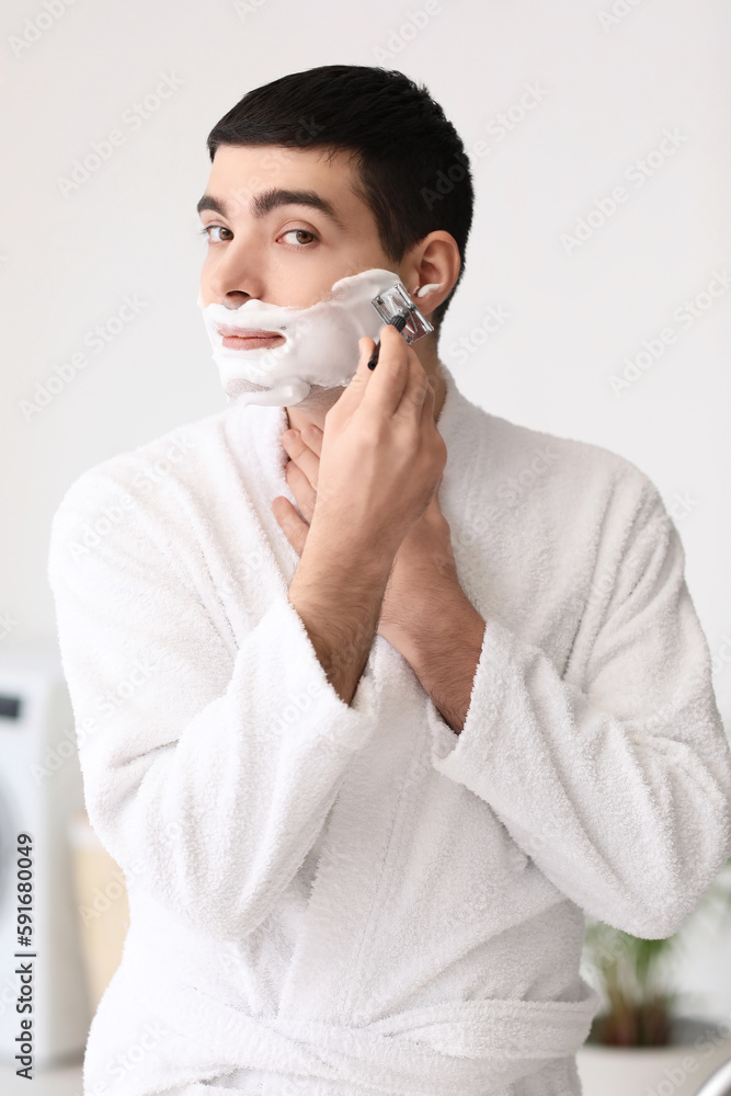 Young man shaving in bathroom