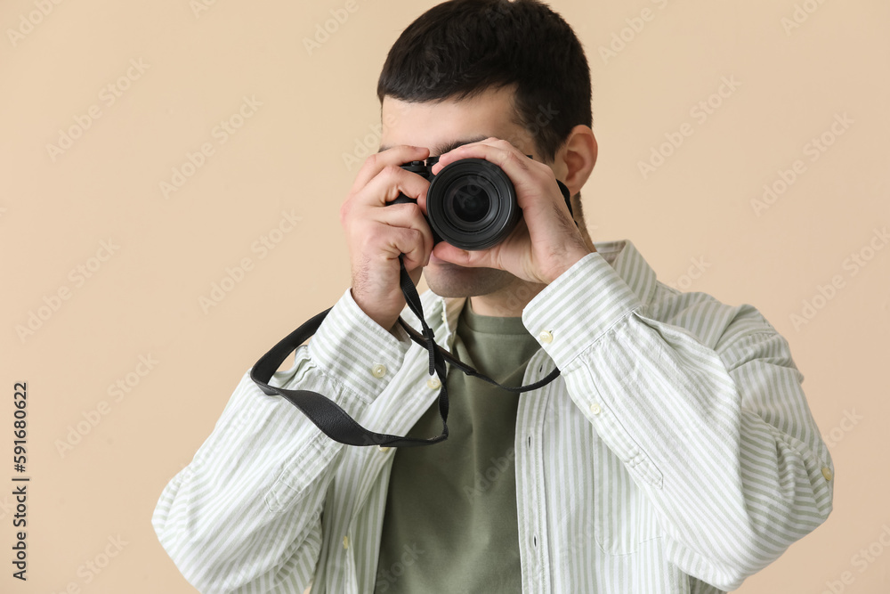Young male photographer with professional camera on beige background, closeup Young male photographer with professional camera on beige background, closeup