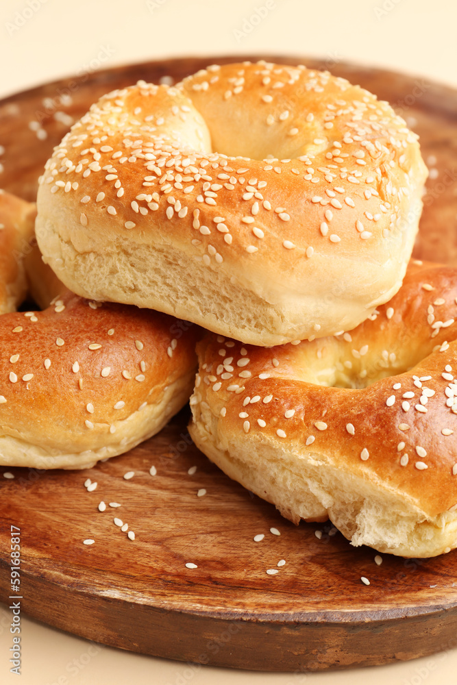 Plate of tasty bagels with sesame seeds on beige background, closeup
