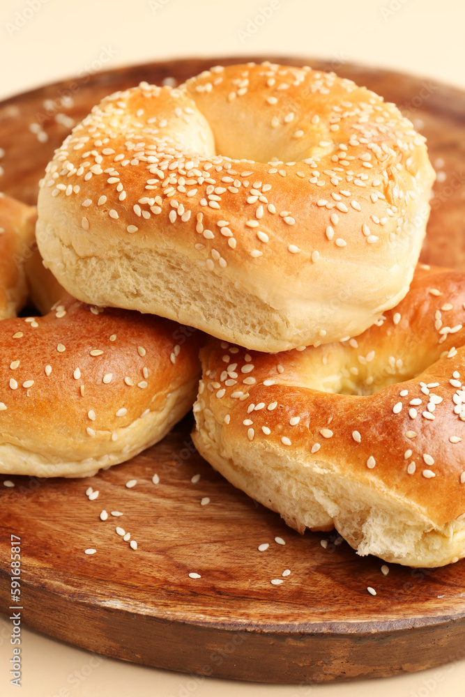 Plate of tasty bagels with sesame seeds on beige background, closeup Plate of tasty bagels with sesame seeds on beige background, closeup