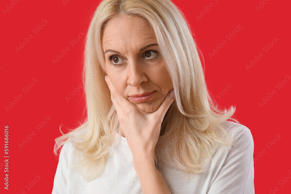 Thoughtful mature woman on red background, closeup Thoughtful mature woman on red background, closeup